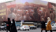 Women walk in front of a banner covering the facade of a building in Tehran, hours before his funeral in Beirut on February 23, 2025. (Photo by Atta Kenare / AFP)
