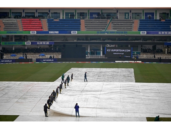 Groundmen cover the pitch as it rains before the start of the ICC Champions Trophy one-day international (ODI) cricket match between Australia and South Africa at the Rawalpindi Cricket Stadium in Rawalpindi on February 25, 2025. (Photo by Farooq NAEEM / AFP)
