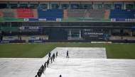 Groundmen cover the pitch as it rains before the start of the ICC Champions Trophy one-day international (ODI) cricket match between Australia and South Africa at the Rawalpindi Cricket Stadium in Rawalpindi on February 25, 2025. (Photo by Farooq NAEEM / AFP)
