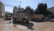 Vehicles of Israeli occupation forces drive down a road amid a weeks-long offensive at the Jenin refugee camp in the occupied West Bank on February 25, 2025. (Photo by Jaafar ASHTIYEH / AFP)
