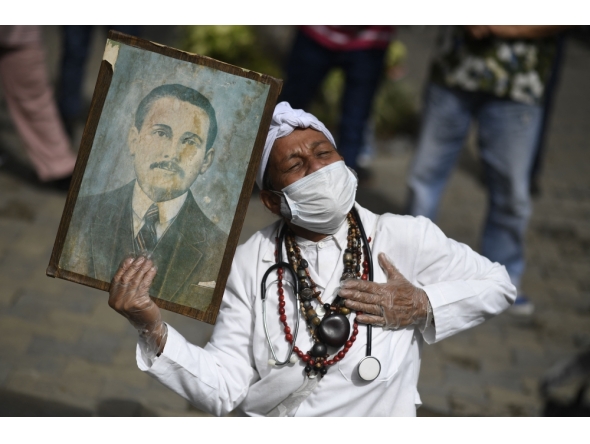 File: A woman holds a portrait of Venezuelan doctor Jose Gregorio Hernandez, also called 