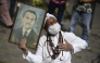 File: A woman holds a portrait of Venezuelan doctor Jose Gregorio Hernandez, also called 