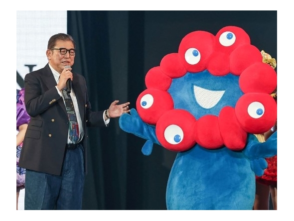 Japan's Prime Minister Shigeru Ishiba stands with Myaku-Myaku, the mascot for the 2025 Osaka World Expo, during a visit to the Tokyo Girls Collection fashion event in the Shibuya district of Tokyo on March 1, 2025. (Photo by Jiji Press / AFP)