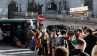 Passengers queue to take a bus from Opera district, in order to reach Paris Charles-de-Gaulle Airport (CDG), as train traffic has been stopped at the Gare du Nord station in Paris on March 7, 2025, following the discovery of a World War II bomb. (Photo by Geoffroy Van Der Hasselt / AFP)