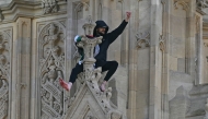 A protester holding a Palestinian flag gestures from the side of the Elizabeth Tower, commonly known by the name of the clock's bell 