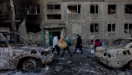 People carry their belongings as they leave their damaged residential building following a strike in Dobropillia, Donetsk region, on March 8, 2025. (Photo by Tetiana DZHAFAROVA / AFP)