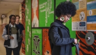 Eighth-grader Ja’ Nae Dorsey (R) unlocks her cell phone pouch after school followed by her twin sister La’ Mae Dorsey (L) and 7th-grader Hayden Jones (C) at Mark Twain Middle School in Alexandria, Virginia, on March 6, 2025. Photo by Jim WATSON / AFP