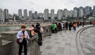 People look at the skyline next to the Jialing river in Yuzhong District in Chongqing in southwestern China on March 6, 2025. (Photo by Hector RETAMAL / AFP)