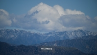 Snow dusted mountains stand on the skyline behind a view of the Hollywood sign following rain storms, as seen from the Kenneth Hahn State Recreation Area, in Los Angeles, California on March 7, 2025. (Photo by Patrick T. Fallon / AFP)
