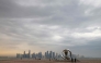 People walk on the Doha waterfront before sunset with the a view of the Qatari capital's skyline in the background on March 9, 2025. (Photo by Karim Jaafar / AFP)