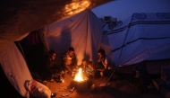 Palestinians gather around a fire to keep warm in Jabalia in the northern Gaza Strip on March 10, 2025. (Photo by Omar Al-Qattaa / AFP)