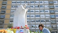 A woman walks next to the statue of John Paul II outside the Gemelli Hospital where Pope Francis is hospitalized in Rome, on March 11, 2025. Photo by Alberto PIZZOLI / AFP