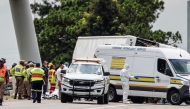 South African emergency services personnel, police and forensic officers stans next to the covered bodies at the scene of a bus accident in Ekurhuleni on March 11, 2025. Photo by WIKUS DE WET / AFP