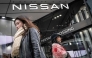 This picture taken on February 5, 2025 shows pedestrians walking past a showroom for Japanese automaker Nissan in Tokyo. Photo by Yuichi YAMAZAKI / AFP