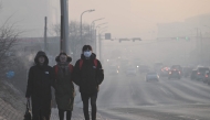 This photo taken on February 18, 2025 shows people walking as motorists commute on a road on a polluted day in Ulaanbaatar, the capital of Mongolia. (Photo by Jade Gao / AFP) 