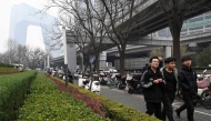 The CCTV Headquarters building (L) is seen as pedestrians walk along the Central Business District (CBD) in Beijing on March 11, 2025. (Photo by ADEK BERRY / AFP)