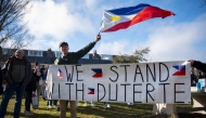 A demonstrator waves a Philippines national flag and holds a banner reading 