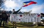 A demonstrator waves a Philippines national flag and holds a banner reading 