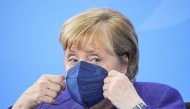 Then German Chancellor Angela Merkel puts onher face mask as she leaves after addressing a press conference following a video meeting with the heads of government of Germany's federal states at the Chancellery in Berlin on November 18, 2021, amid the novel coronavirus / COVID-19 pandemic. Photo by Michael Kappeler / POOL / AFP