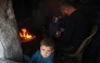 A child looks on as his family prepares a fast-breaking iftar meal in the Bureij camp for Palestinian refugees in the central Gaza Strip on March 11, 2025 during the Muslim holy fasting month of Ramadan. (Photo by Eyad BABA / AFP)