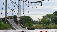 In this aerial view rescuers search for missing persons after a suspension bridge collapsed in Duale, Guayas province, Ecuador on March 20, 2025. The collapse in Ecuador of a busy 200-metre-long suspension bridge carrying several vehicles left at least one dead, five injured and two missing, authorities said in a new assessment on Thursday. (Photo by MARCOS PIN / AFP)
