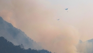 Helicopters try to extinguish a fire after a wildfire broke out in the southeastern county of Sancheong on March 22, 2025. (Photo by YONHAP / AFP)