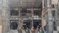 Soldiers of the Sudanese army or affiliated forces pose for a picture while pumping their fists at the damaged presidential palace after recapturing the complex from RSF paramilitaries in Khartoum on March 21, 2025. (Photo by AFP)