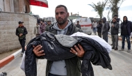 A Palestinian man carries the body of a child killed in an Israeli strike, in the yard of the Indonesian hospital in Beit Lahia in the northern Gaza Strip on March 22, 2025. (Photoby Bashar Taleb / AFP)