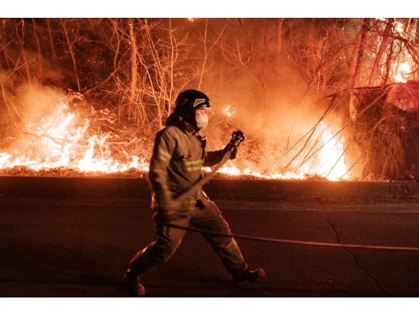 A firefighter prepares to spray water as wildfires spread along the slopes in Uiseong, South Korea, on March 24, 2025. Photo by YASUYOSHI CHIBA / AFP.