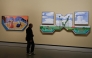 A visitor looks at paintings by British painter David Hockney ahead of the opening of the exhibition entitled 