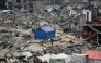 People stand outside their tent set up on the rubble of a destroyed building at the Jabalia camp for displaced Palestinians in the northern Gaza Strip on April 8, 2025. Photo by Bashar TALEB / AFP