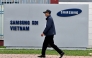 This photo taken on April 8, 2025 shows a man walking past the logo of Samsung Electronics on a billboard in Bac Ninh province. (Photo by Nhac Nguyen / AFP) 