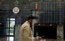 A stockbroker walks past share prices on a financial market board during a trading session at the Pakistan Stock Exchange (PSX) in Karachi on April 9, 2025. (Photo by Rizwan TABASSUM / AFP)
