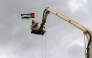 A demonstrator being raised by a crane holds up a Palestinian flag during a rally in solidarity with Palestinians in the Gaza Strip and in condemnation of US strikes, in Yemen's capital Sanaa on April 11, 2025. (Photo by Mohammed Huwais / AFP)
