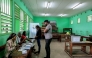 Voters receive their ballot papers from electoral officials at the Lycee Leon Mba polling station in Libreville on April 12, 2025 during Gabon's presidential election. (Photo by Daniel Beloumou Olomo / AFP)