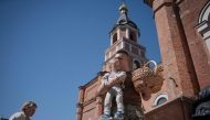 An Ukrainian serviceman holds his toodler and a basket with traditional Easter cakes and eggs during Easter service outside the Church of Ivan the Theologian, in Kharkiv, on April 20, 2025, amid the Russian invasion of Ukraine. (Photo by Ivan SAMOILOV / AFP)
