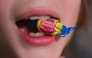 A boy holds a wrapped Dubble Bubble Bubble Gum candy in his mouth, a product that uses Red Dye # 3, in this illustration photograph on December 27, 2024. Photo by ROBERTO SCHMIDT / AFP