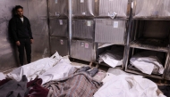 A Palestinian man stand over covered bodies, killed in an Israeli strike on a school-turned-shelter, at the morgue of the Al-Shifa hospital in Gaza City on April 23, 2025. Photo by Omar AL-QATTAA / AFP