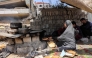 A woman bakes pita bread loaves in an oven by a tent in Gaza City on April 21, 2025. (Photo by Omar AL-QATTAA / AFP)