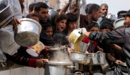 People queue with pots to receive charity meals from a kitchen in Beit Lahia in the northern Gaza Strip on April 24, 2025. Israel on March 18 resumed its intense military offensive in the Palestinian territory after a ceasefire deal that came into effect on January 19 fell apart two months later over differences regarding its next phase. (Photo by Bashar TALEB / AFP)