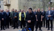 Ukraine's President Volodymyr Zelensky talks to the press as diplomats stands behind him near a destroyed residential building following a Russian missile attack in Kyiv on April 25, 2025, amid the Russian invasion of Ukraine. (Photo by Tetiana DZHAFAROVA / AFP)
