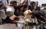People queue with pots to receive charity meals from a kitchen in Beit Lahia in the northern Gaza Strip on April 24, 2025. (Photo by Bashar Taleb / AFP)