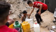 A boy fills up containers with water from the remaining water still left in underground pipes, in Beit Lahia in the northern Gaza Strip on April 24, 2025. Photo by Bashar Taleb/ AFP