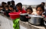 Children queue with pots to receive charity meals from a kitchen in Beit Lahia in the northern Gaza Strip on April 24, 2025. Photo by Bashar TALEB / AFP