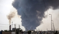 A thick plume of smoke billows as motorists drive their vehicles along a highway near the source of an explosion at the Shahid Rajaee port dock southwest of Bandar Abbas in the Iranian province of Hormozgan on April 26, 2025. Photo by Mohammad Rasole MORADI / IRNA / AFP.