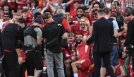 Liverpool's English midfielder #19 Harvey Elliott, Liverpool's Egyptian striker #11 Mohamed Salah, Liverpool's English defender #66 Trent Alexander-Arnold, Liverpool's English defender #02 Joe Gomez, Liverpool's Brazilian goalkeeper #01 Alisson Becker, Liverpool's Japanese midfielder #03 Wataru Endo pose with teammates after winning the English Premier League football match between Liverpool and Tottenham Hotspur at Anfield in Liverpool, north west England on April 27, 2025. Liverpool won the match 5-1, making them the winners of the Premier League title. (Photo by Paul ELLIS / AFP) 