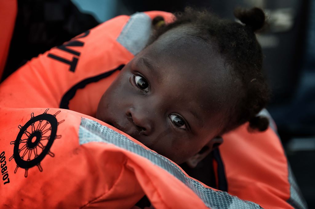 A child from African origin looks on as she is rescued from a distressed vessel by a member of Proactiva Open Arms NGO in the mediteranean sea some 20 nautical miles north of Libya on October 3, 2016. AFP / ARIS MESSINIS