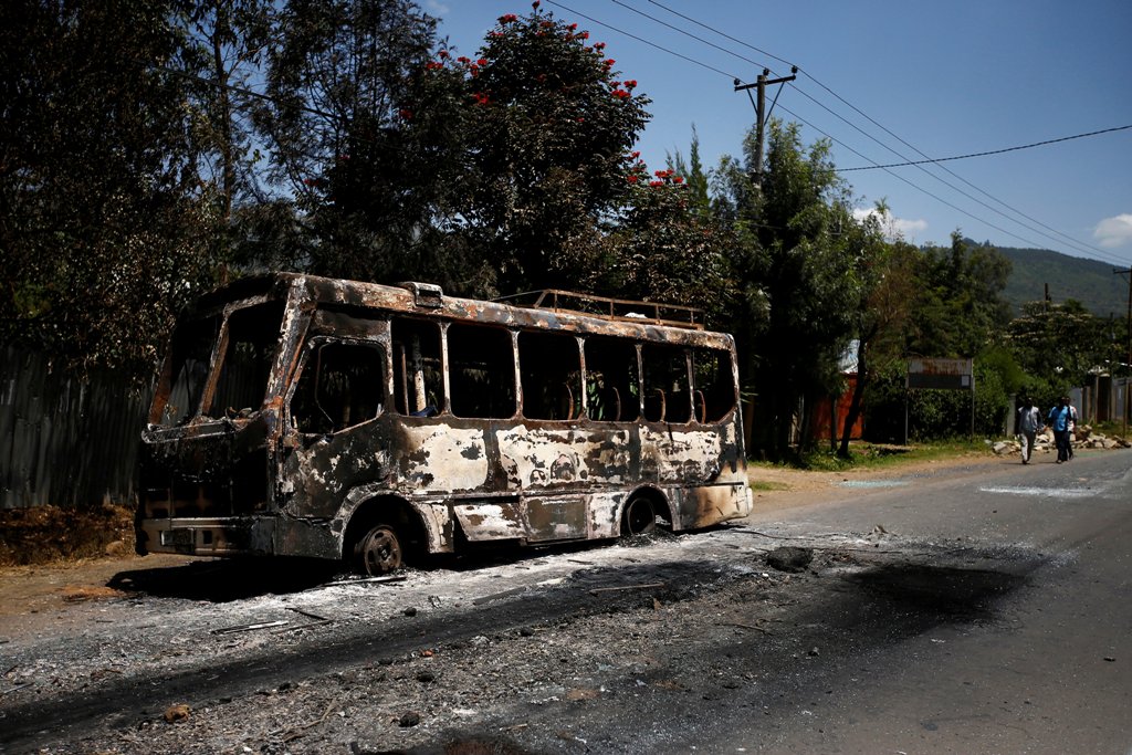 Men walk past a bus that was torched during protests in the town of Sebeta, Oromia region, Ethiopia, October 8, 2016. REUTERS/Tiksa Negeri
