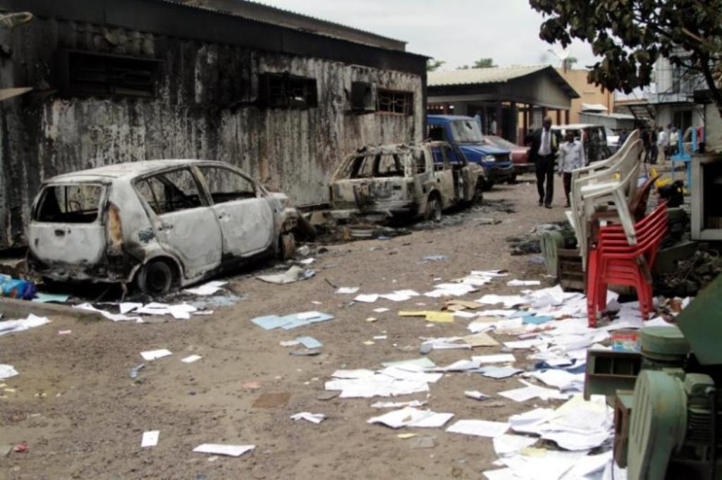 Congolese civilians walk past a house and vehicles which were burnt during anti-government protests / Reuters.