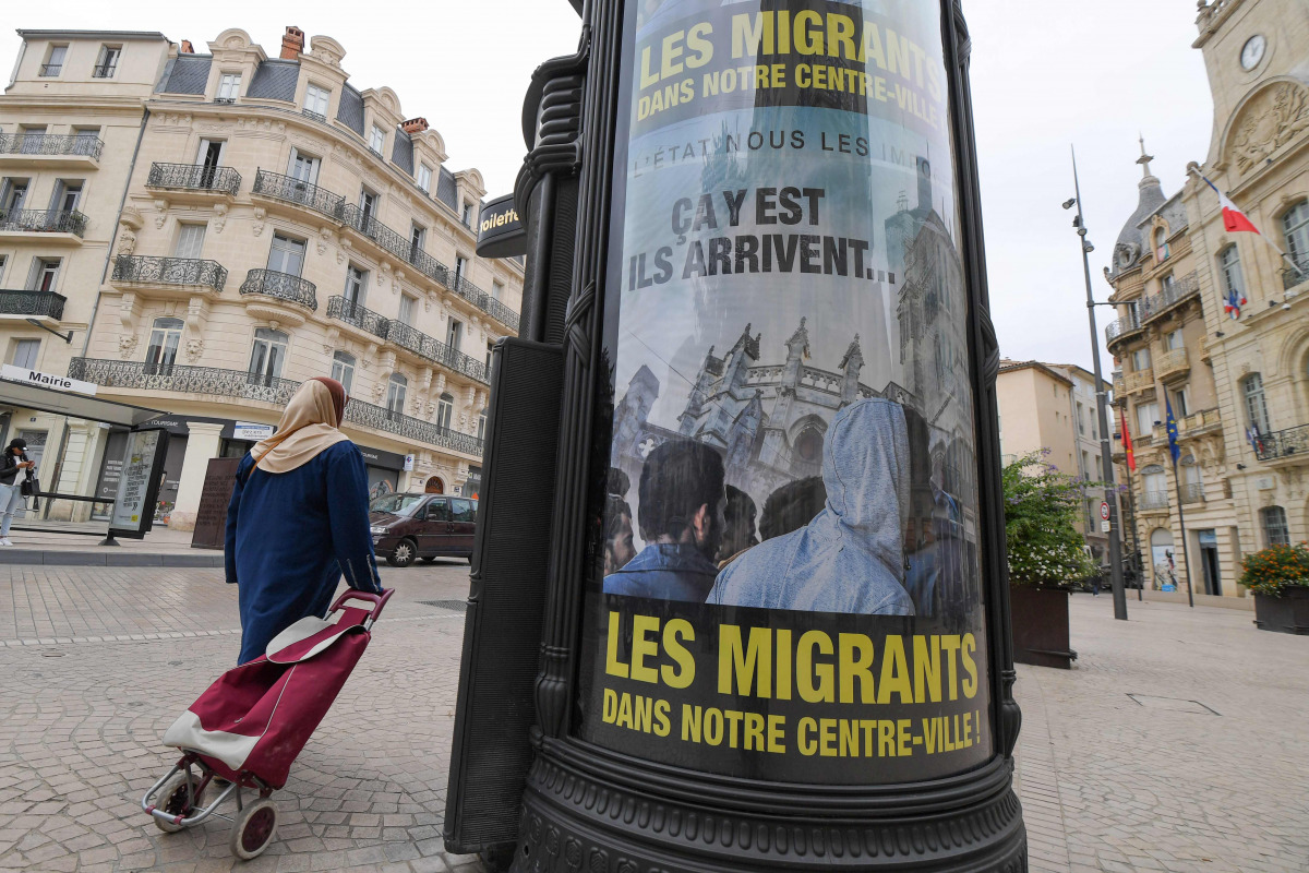 A woman walks by a poster reading 